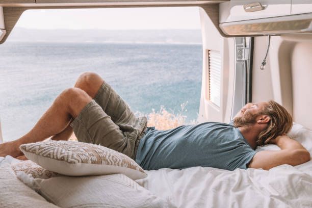istock Man lying in a van looking at ocean 1392328693