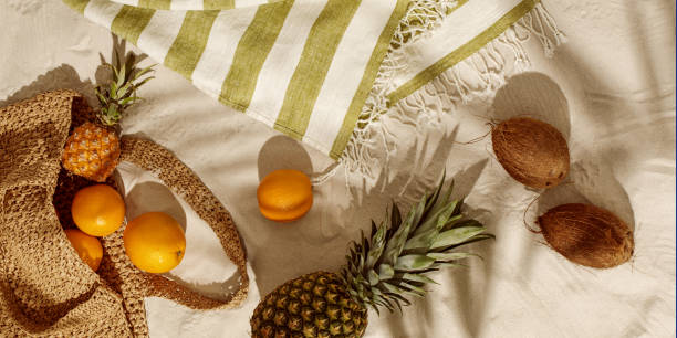 istock Fresh oranges, pineapple, coconuts falling out from woven bag on sandy beach. Vintage camera, sunglasses on linen beach towel with fringes. Tropical holidays concept 1392328798