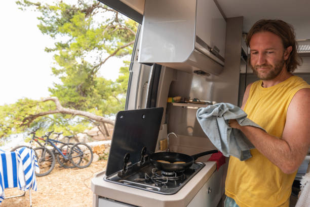 istock Man cooking in a camper-van, ocean view 1392328890