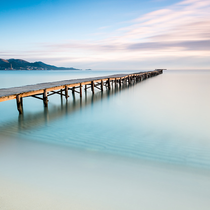 Calm sea in a beauty sand beach with long pier.