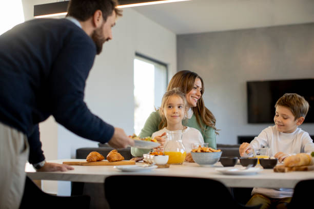 istock Young happy family talking while having breakfast at dining table 1392333964
