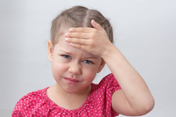 Child with headache holding hand on forehead