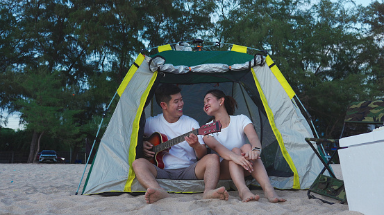 Young Couple in tent on the beach sunset, romantic relationships in vacation holidays, enjoying with travel and resting on summer vacation or holiday concept.