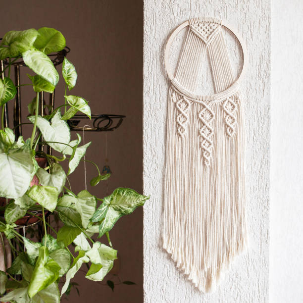 istock Handmade cotton macrame Dream catcher on white wall background. Traditional amulet for protecting sleep.  Macrame lace home decor on the wall with green leaves. Woman hobby. 1392338665