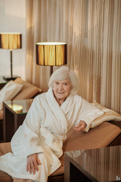 istock A good-looking old lady in a white robe in a hotel room 1392342570