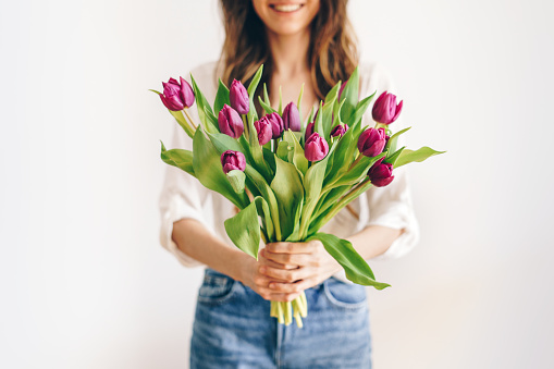 White-pink roses in the hands of a happy woman. Rose petal close-up. Beautiful holiday spring bouquet. Florist girl with blossom flower. Fresh floral bunch. Romantic surprise from a loved one