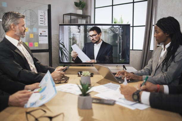 istock Group of skillful multiethnical businesspeople looking at screen, having video conference 1392343525