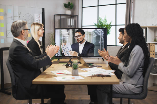 istock Group of multiethnical businesspeople clapping hands and looking at screen, having video conference 1392343666