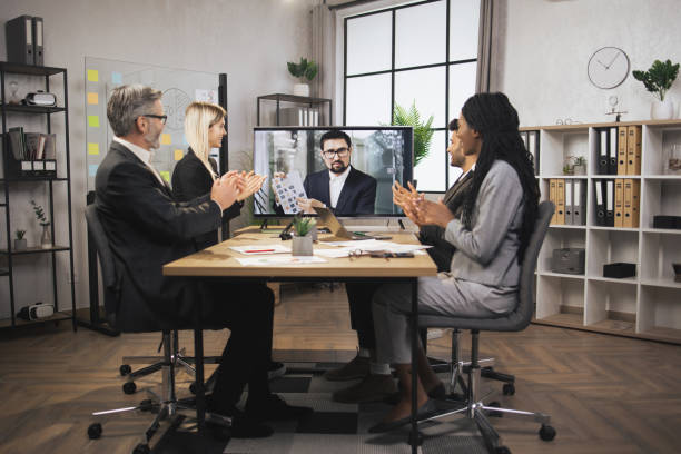 istock Group of multiethnical businesspeople clapping hands and looking at screen, having video conference 1392343672
