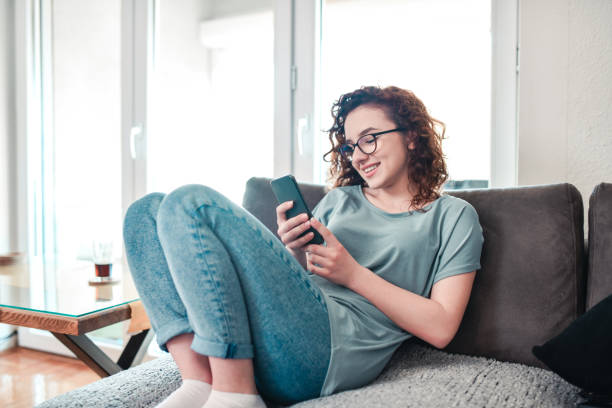 istock Curly Female Beauty Having A Relaxing Day Spent With Smartphone On Sofa 1392343704