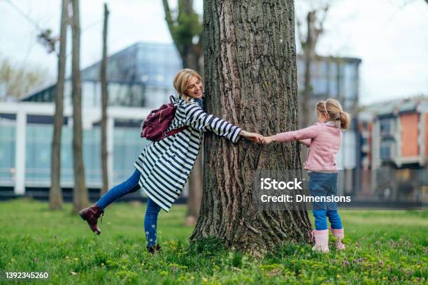 Family Of Two Standing In Park And Hugging Tree Stock Photo - Download Image Now - Child, Adult, Affectionate
