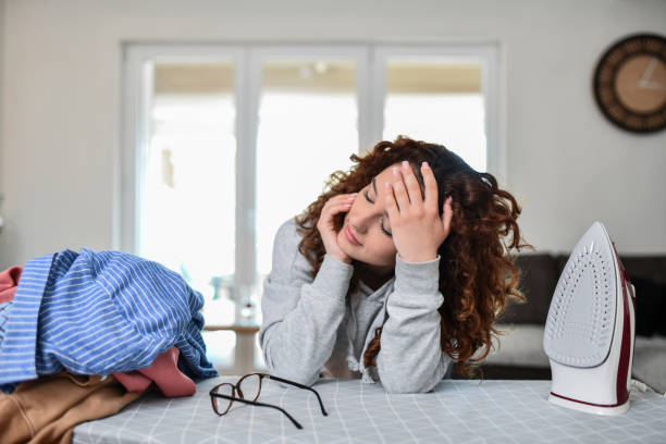 Female Getting Tired While Ironing Clothes At Home