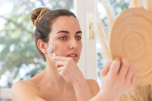 istock Portrait of young bautiful woman using rose quartz roller on her face 1392345700