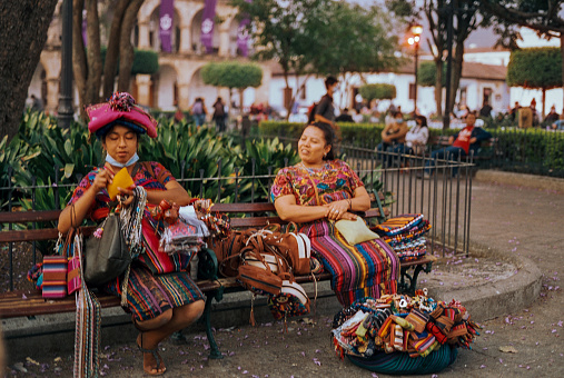 Merida, Mexico - February 11, 2022: Two women sitting on the bench and selling traditional Mexican souvenirs