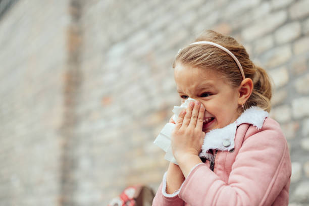 istock Sick little girl blowing nose in a tissue 1392347249