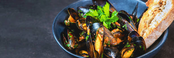 A bowl of delicious steamed mussels with grilled bread. stock photo