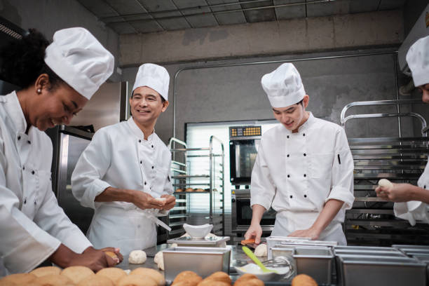 istock Chefs team in uniforms prepare to bake bread and pastry in stainless kitchen. 1392348846