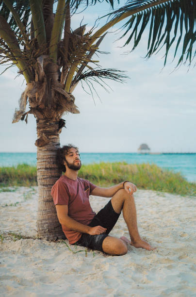 istock Man sitting under the palm tree on  Isla Mujeres beach 1392349394