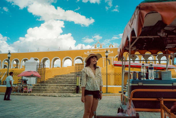 frau zu fuß in der stadt izamal in mexiko - women rear view one person arch stock-fotos und bilder