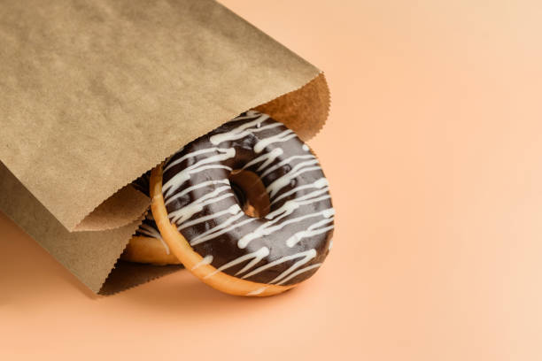 istock paper bag with chocolate donuts close-up. 1392349783
