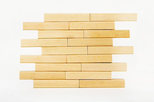 Close-up wall built with toy wooden blocks. wooden brick tower on a white background.