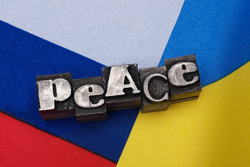 Full-size close-up of Russian and Ukrainian flag with word Peace made of old heavily used metal lead printer filets on it as concept for peace in Eastern Europe during war between Urkaine and Russia