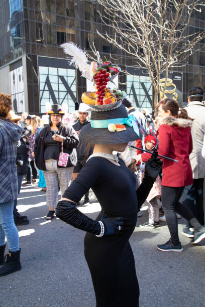 Easter Bonnet Parade 2022 New York City, NY- April 17,2022: A girl dressed in costume with the theme of Breakfast at Tiffany's, poses for the crowd during the annual Easter Bonnet Parade on Fifth Avenue. bonnet hat stock pictures, royalty-free photos & images