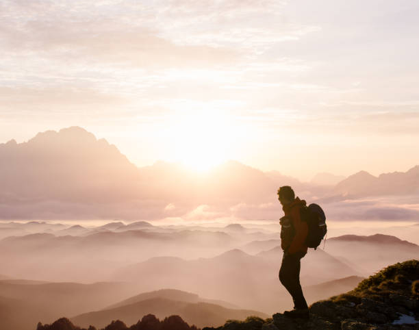 istock Man in beautiful mountain landscape at sunset 1392356178