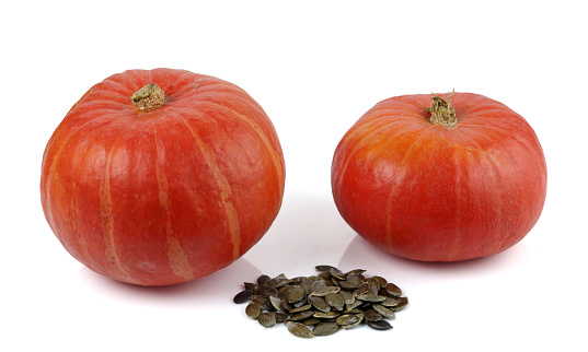Two red kuri squashes and a bunch of peeled seeds. Isolated on a white background.