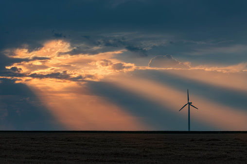 Wind turbine in field at sunset