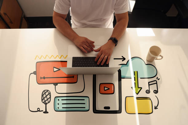 un homme fait du plateau pour créer du contenu numérique sur son ordinateur portable avec des icônes de ligne - social media marketing branding sign photos et images de collection