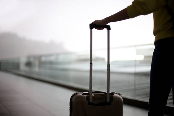 An Asian woman is waiting with her luggage.