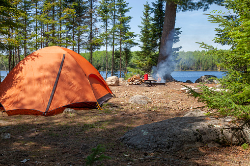 Orange tent and campfire on a lake in the Boundary Waters of northern Minnesota during summer