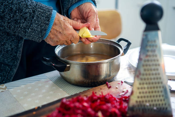 istock senior woman cutting potatoes or preparing meal at kitchen, hands view 1392362942