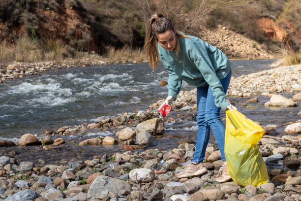 istock Save environment concept, woman collecting garbage and plastic on the river 1392364856