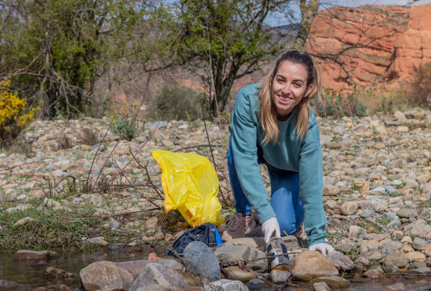 istock Wildlife volunteer smiling using garbage bag and collecting litter in the river 1392364890