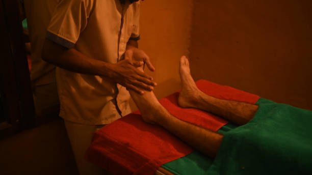 мужчина, принимающий аюрведическую лечебную терапию для расслабляющего массажа ног - chakra ayurveda recovery herbal medicine стоковые фото и изображения