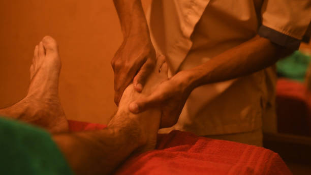 мужчина, принимающий аюрведическую лечебную терапию для расслабляющего массажа ног - chakra ayurveda recovery herbal medicine стоковые фото и изображения