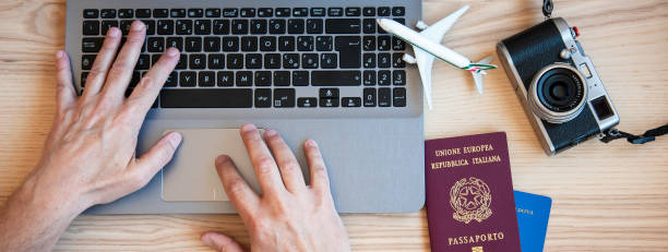 istock Horizontal banner or header with male hands typing on modern laptop for booking an airplane flight - Man plans couple tour with passports on the desk for holiday - Different nationality passports 1392370688