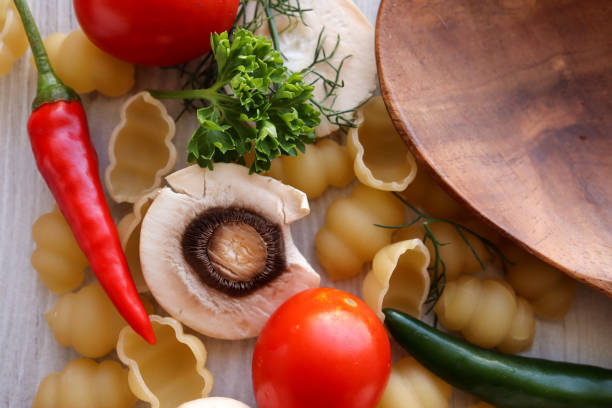 Ingredients for a pasta salad or bake including mushrooms, gnocchi pasta shells, tomatoes, chillies, parsley and dill