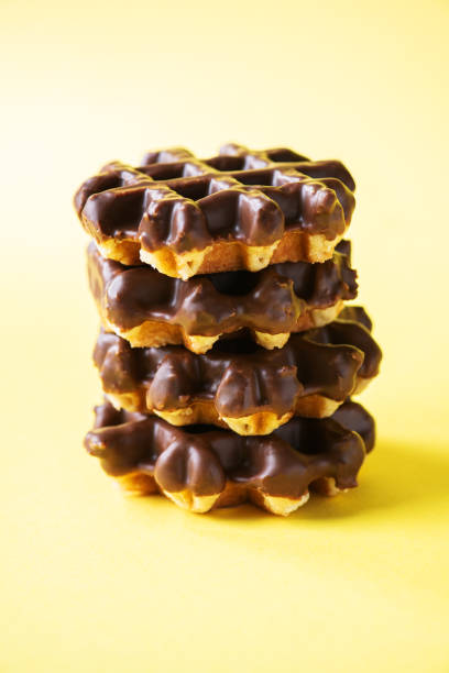 istock Stack of chocolate waffles. Close up and yellow background, copy space. 1392372985