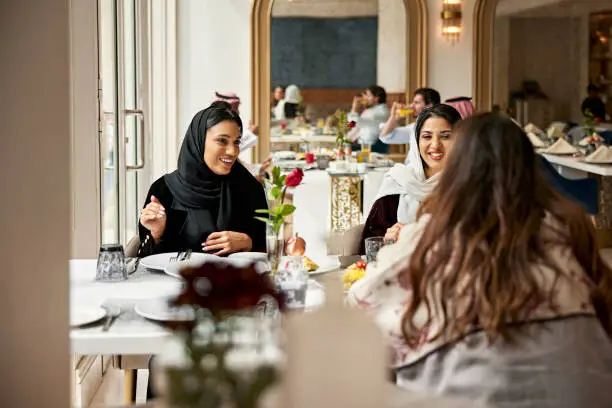 Photo of Middle Eastern women enjoying meal in hotel restaurant