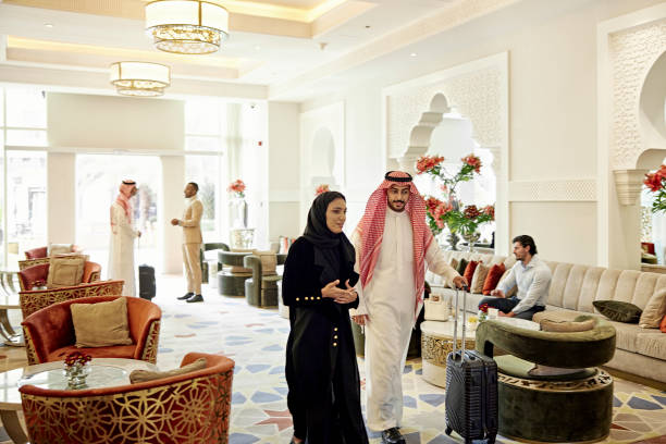 Guests at luxury hotel in Riyadh, Saudi Arabia Mixed age range of people in traditional Middle Eastern attire walking, talking, and relaxing in lobby with modern Islamic architectural design and decor. kaffiyeh stock pictures, royalty-free photos & images