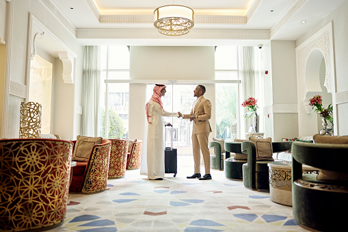Empresario saudí estrechando la mano de un cliente en el vestíbulo del hotel photo