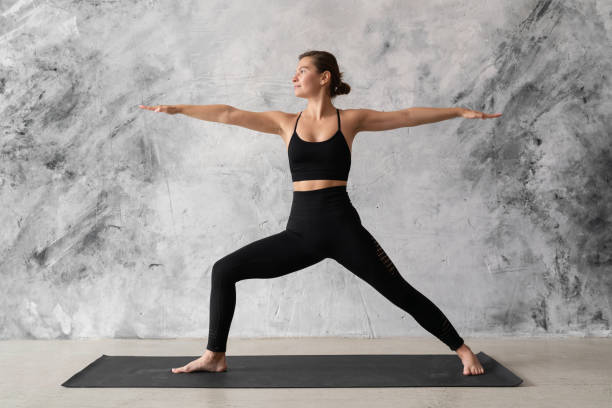 istock Young woman practicing yoga warrior pose, virabhadrasana against grunge wall 1392376464