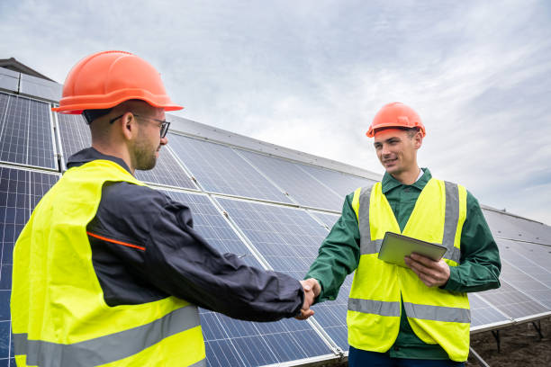 istock Workers in work clothes greet each other by the hand before starting work on solar panels. 1392379295