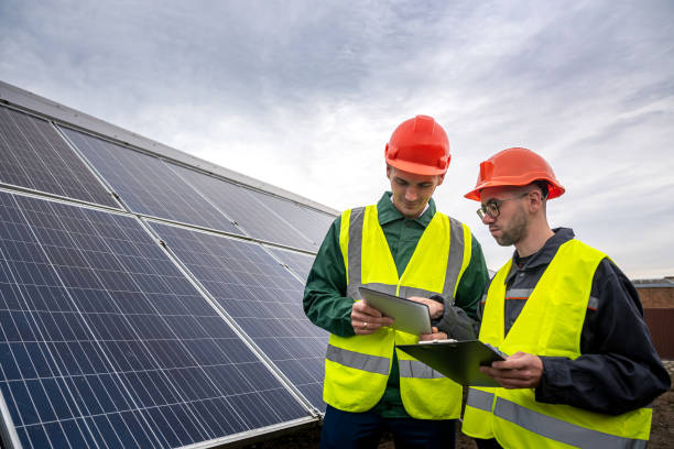 istock two strong skilled men in helmets and vests stand and talk in solar panels. 1392380314