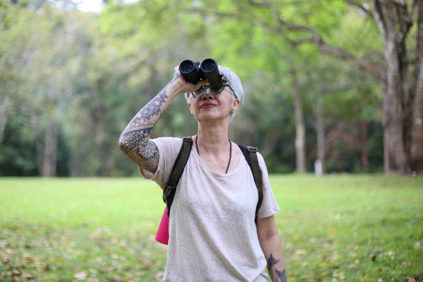istock senior woman using binoculars to spot animals and things while hiking with backpacks and trekking in the forest. Concept of active lifestyle on retirement. 1392385667