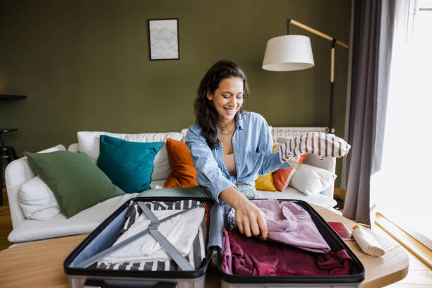 istock Young woman sitting on the couch and packing suitcase 1392385985