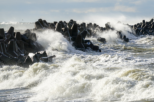 coastal storm in the Baltic Sea, big waves crash against the concrete breakwater at the port entrance